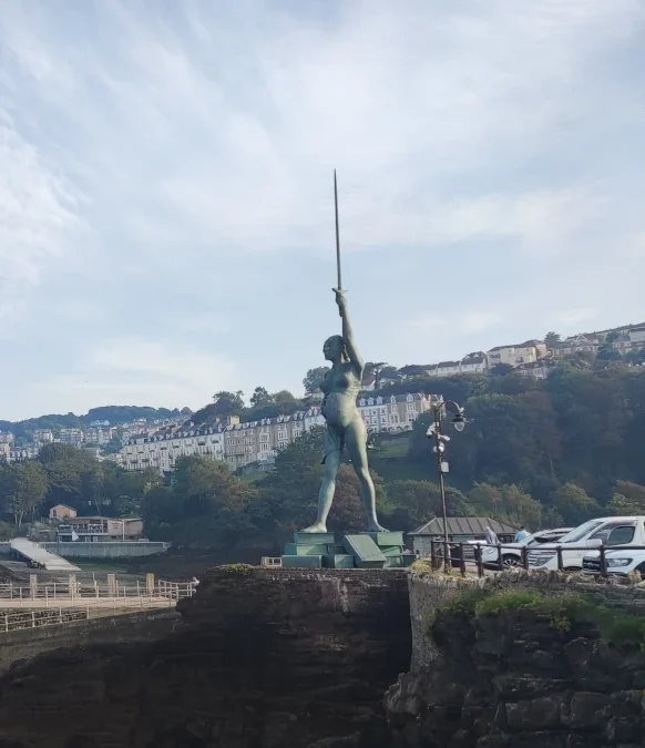 Verity statue by Damien Hirst standing at Ilfracombe harbour entrance, overlooking the sea and hillside town