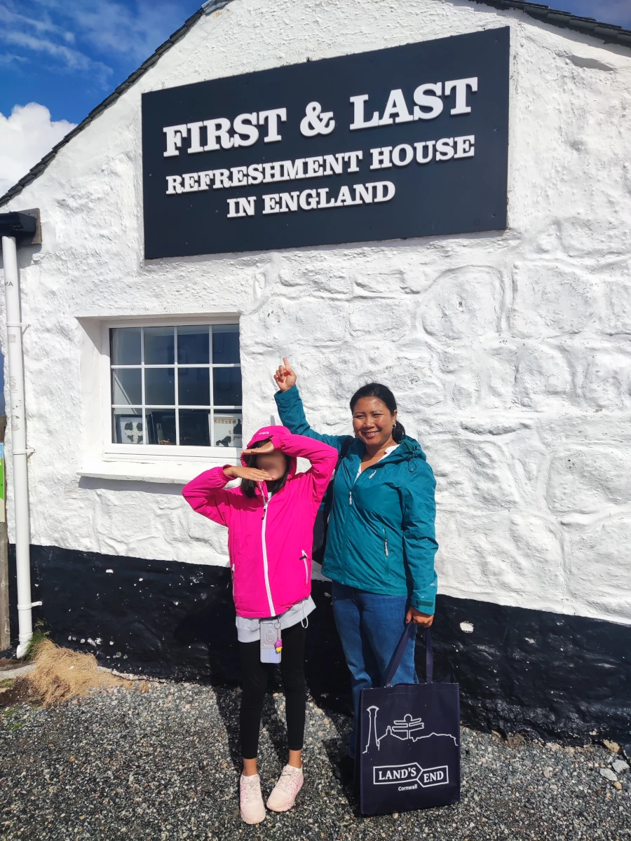 Visitors posing outside the First and Last House refreshment building at Land's End