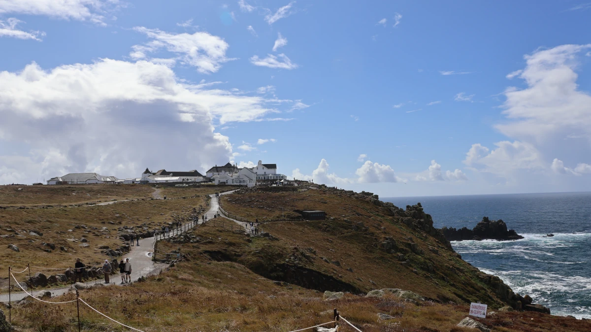 Path leading toward the Land's End buildings along the clifftop headland with the Atlantic below