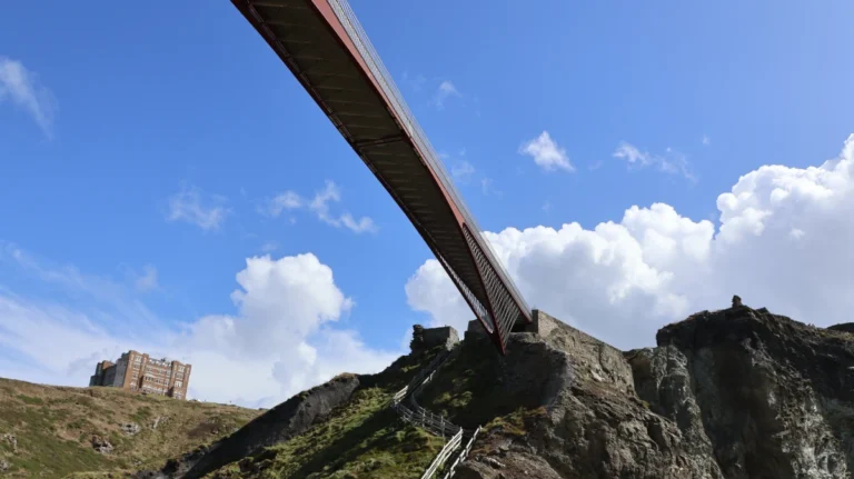 View up at the underside of Tintagel Castle Bridge with the ruins and cliffs below