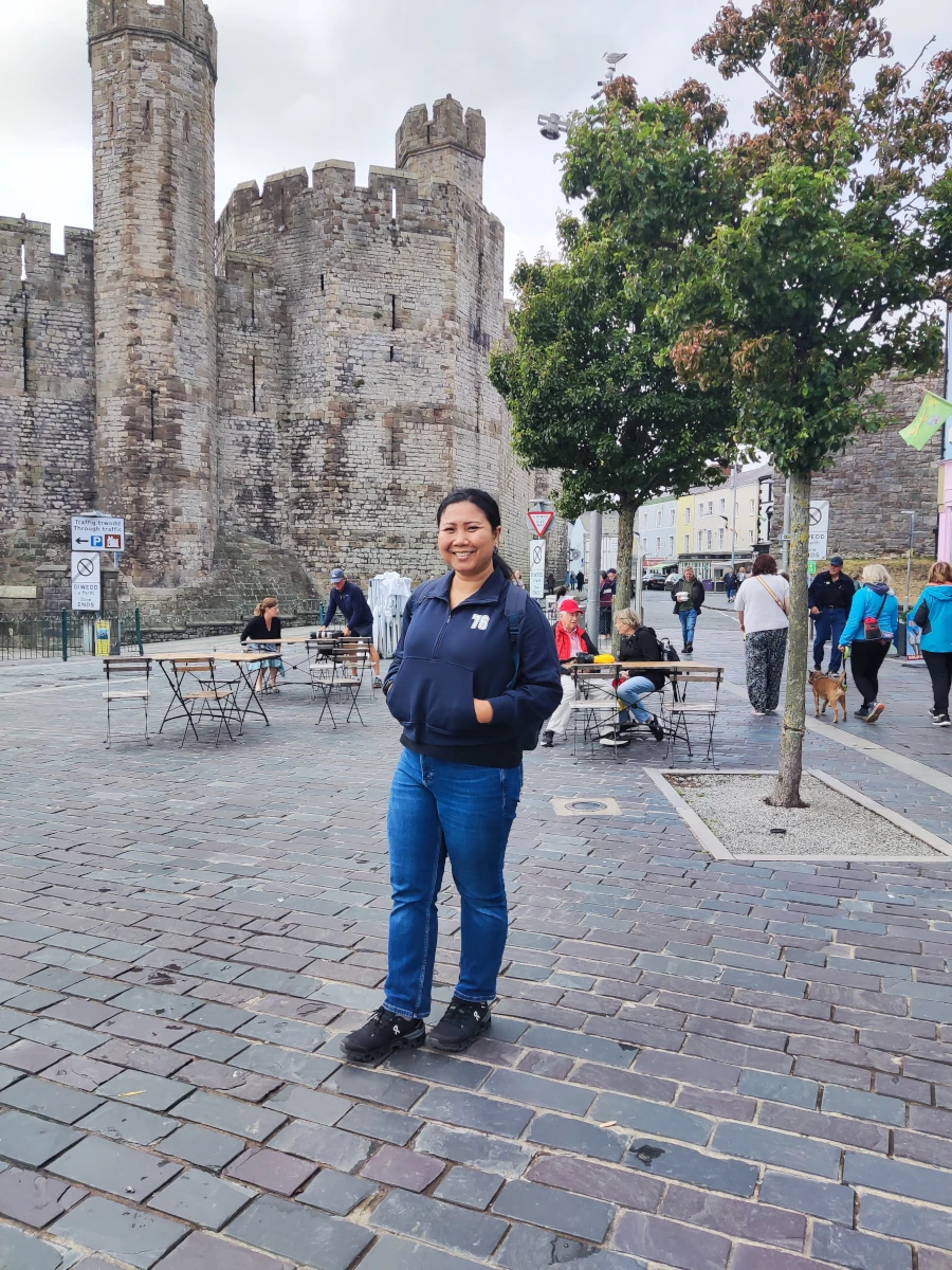 Visitor standing in front of Caernarfon Castle's tower and walls in the town square