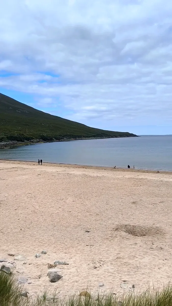 Wide sandy beach at Dugort, Achill Island, Co. Mayo, with calm water and the green slope of Slievemore running down to the sea