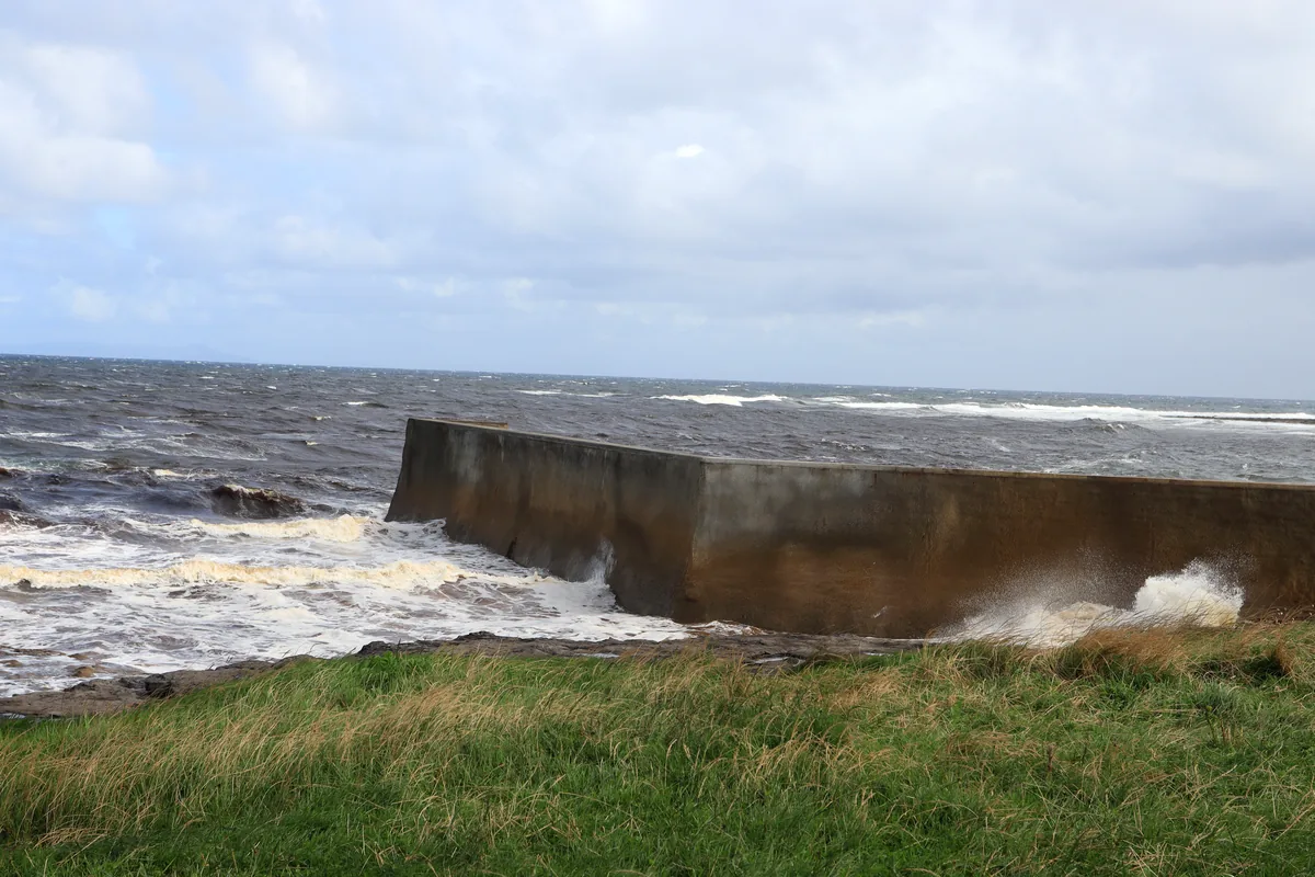 Waves breaking against the concrete pier at Easkey beside Roslee Castle, County Sligo, Ireland, on a very windy day.