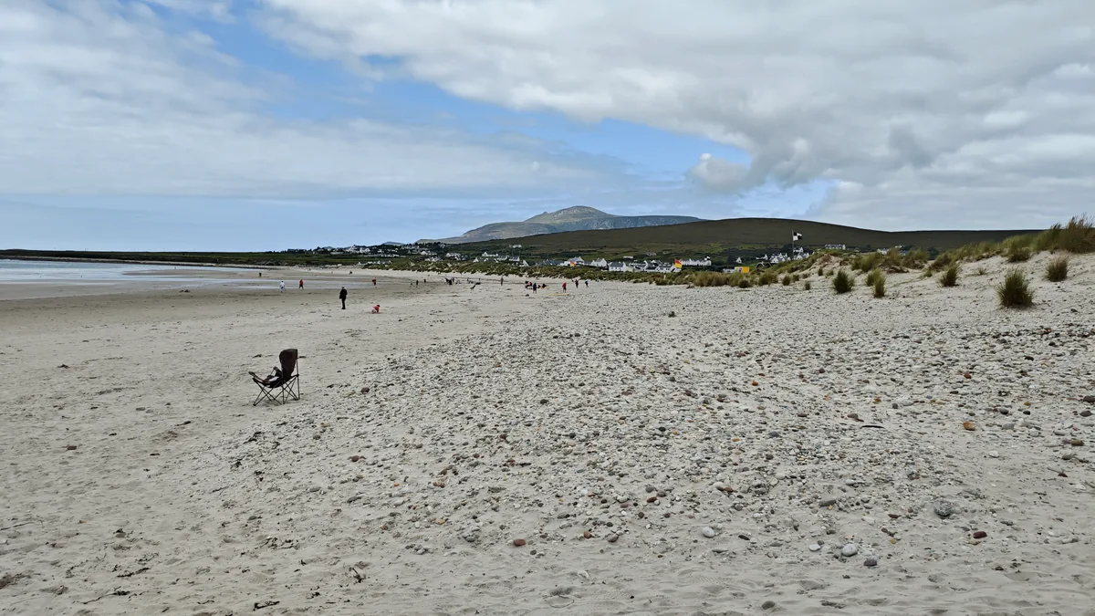 Keel Beach at the Keel village end on Achill Island, Co. Mayo, with dunes, beach flags, visitors and Slievemore in the distance
